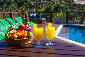 - deux verres de jus et une corbeille de fruits sur une table près de la piscine dans l'établissement Coronado Inn Hotel, à Búzios