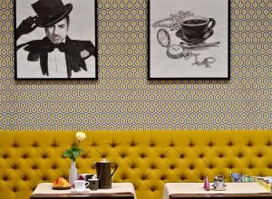 a restaurant with a yellow couch and pictures on the wall at Hotel Capitolina City Chic in Cluj-Napoca