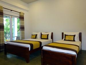 two beds in a room with a window at Kadulla Resort in Habarana