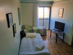 Habitación pequeña con cama y TV. en Flat Saint Paul Residence, en Bauru