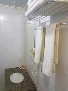 ein Badezimmer mit weißen Handtüchern auf einem Kleiderständer in der Unterkunft Flat Saint Paul Residence in Bauru