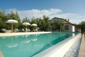 a blue swimming pool with chairs and umbrellas at Spazzavento Vinci - Agriturismo in Vinci