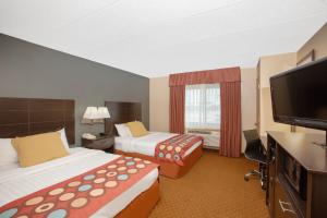 a hotel room with two beds and a television at AmericInn by Wyndham Coralville in Coralville