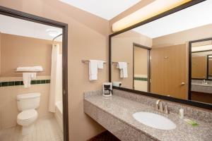 a bathroom with a sink, toilet and mirror at AmericInn by Wyndham Coralville in Coralville