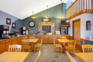 un restaurant avec des tables et des chaises en bois et un comptoir dans l'établissement AmericInn by Wyndham Coralville, à Coralville