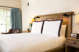 a bedroom with a large white bed and a chair at North Block Hotel in Yountville