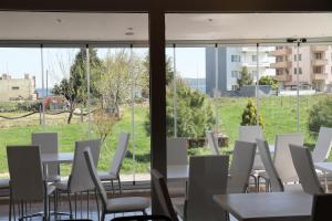 a room with white chairs and tables and windows at Boss 2 Hotel in Eceabat