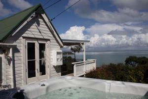 a bath tub in front of a house with a view of the water at The Settlers Hut in Oneroa
