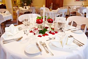 a table with white table cloth and red roses on it at Berghotel Hammersbach in Grainau