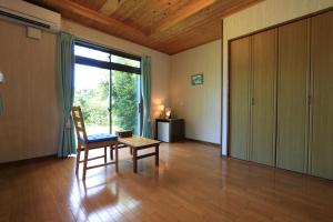ein Wohnzimmer mit einem Sessel, einem Tisch und einem großen Fenster in der Unterkunft Minshuku nicoichi in Yakushima