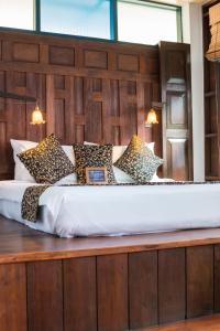 a large bed with a wooden headboard and many pillows at Pak Chiang Mai in Chiang Mai