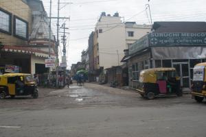 una calle de la ciudad con dos vehículos pequeños estacionados en la calle en Sewak Lodge, en Silchar