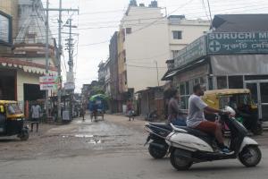 a man riding a scooter on a city street at Sewak Lodge in Silchar