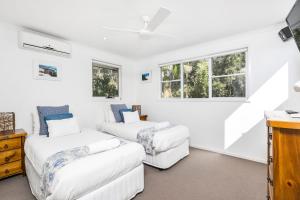 a white room with two beds and windows at A SWEET ESCAPE - Serenity on Sallywattle in Suffolk Park