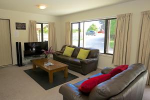 a living room with a leather couch and a television at Crescent House in Wanaka