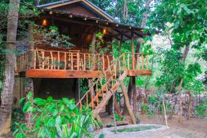 a tree house in the woods with a wooden staircase at girilena resort in Dambulla