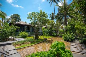 a garden with a house and palm trees at Baba Beach Club Natai Luxury Pool Villa Hotel by Sri panwa - SHA Plus in Natai Beach