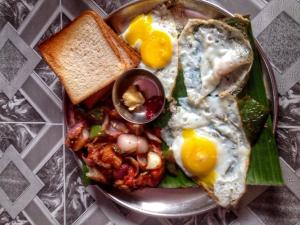 een bord ontbijtproducten met eieren en toast bij Thilak Home Stay in Hampi