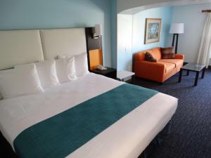 um quarto de hotel com uma cama grande e uma cadeira em Best Western Plus Orlando Lake Buena Vista South Inn & Suites em Kissimmee