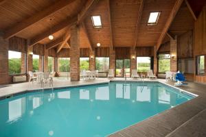 a swimming pool in a large building with tables and chairs at Baymont by Wyndham Warrenton in Warrenton