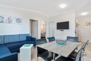 a living room with a blue couch and a table at Horrocks Beach Caravan Park in Horrocks