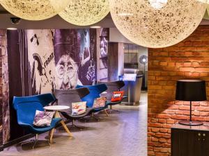 a lobby with chairs and a wall with a mural at ibis London City - Shoreditch in London