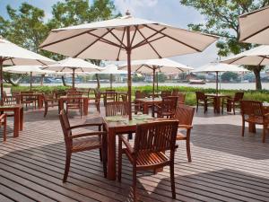 a group of tables and chairs with umbrellas on a deck at Ibis Bangkok Riverside in Bangkok