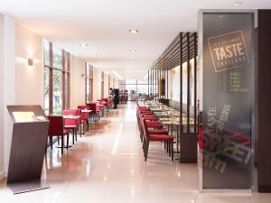 a dining room with tables and red chairs at Ibis Bangkok Riverside in Bangkok