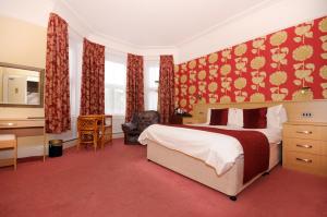 a bedroom with a bed and a desk and a chair at Denewood Hotel in Bournemouth