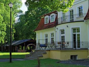 Una gran casa blanca con porche y escaleras. en Hotel Księżycowy Dworek, en Kętrzyn