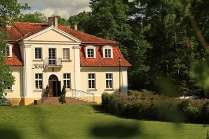 een groot wit huis met een rood dak bij Hotel Księżycowy Dworek in Kętrzyn