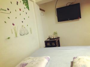 Schlafzimmer mit einem Bett mit einem TV und Schmetterlingen an der Wand in der Unterkunft Dongyin First Homestay in Dongyin/