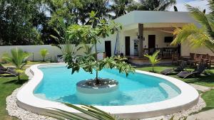 a pool with a tree in the middle of a yard at Positano Alona Beach Panglao in Panglao