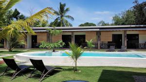 a swimming pool with two chairs and a house at Positano Alona Beach Panglao in Panglao