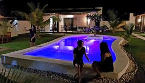 two women sitting next to a swimming pool at night at Positano Alona Beach Panglao in Panglao