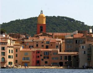 a group of buildings with a clock tower on a hill at Elegante appartmento nel quadrato d'oro a St Tropez in Saint-Tropez
