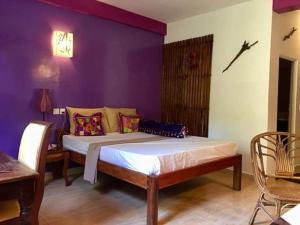 a bedroom with a bed and a purple wall at Auberge de la Plage in Kep