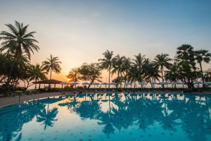 a pool with palm trees and a sunset in the background at Regent - Chalet, Hua Hin in Cha Am