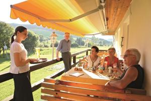 un grupo de personas sentadas alrededor de una mesa comiendo en Akzent Hotel Kaltenbach en Triberg