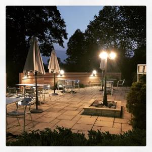 a patio with tables and chairs and umbrellas at night at Logis Le Relais de la Voie Sacrée in Issoncourt
