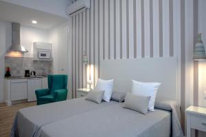 ein Schlafzimmer mit einem Bett und einem grünen Stuhl in der Unterkunft Hotel Apartamentos MPD in Merida