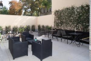 a patio with black chairs and tables and a hedge at La Cave de l'Avenue de champagne in Épernay