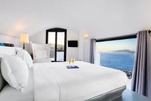 a bedroom with a white bed with a view of the ocean at Grand Ambassador Santorini Hotel in Akrotiri