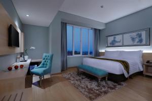 a bedroom with a bed and a desk and a window at ASTON Banyuwangi Hotel and Conference Center in Banyuwangi