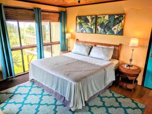a bedroom with a large bed and a large window at Hamakua House and Camping Cabanas in Pepeekeo