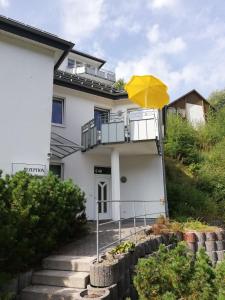 ein gelber Regenschirm vor einem weißen Haus in der Unterkunft Dorf-Quartier in Willingen