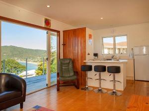 a kitchen with a refrigerator and a counter with chairs at Pretty on Paku, Tairua - Cottage in Tairua