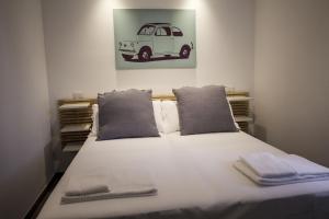 a bed with two pillows and a picture of a car at Rosa's House Rome Airport in Fiumicino