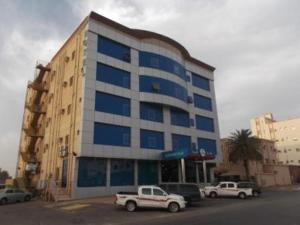 a large building with cars parked in front of it at Arabian Palm Hotel in Rabigh