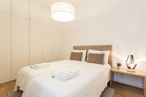 リスボンにあるFLH Restauradores Elegant Placeの白いベッドルーム(白いシーツとランプ付きのベッド付)